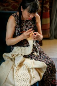 A woman engaged in crocheting indoors, focused and serene, in a cozy setting.
