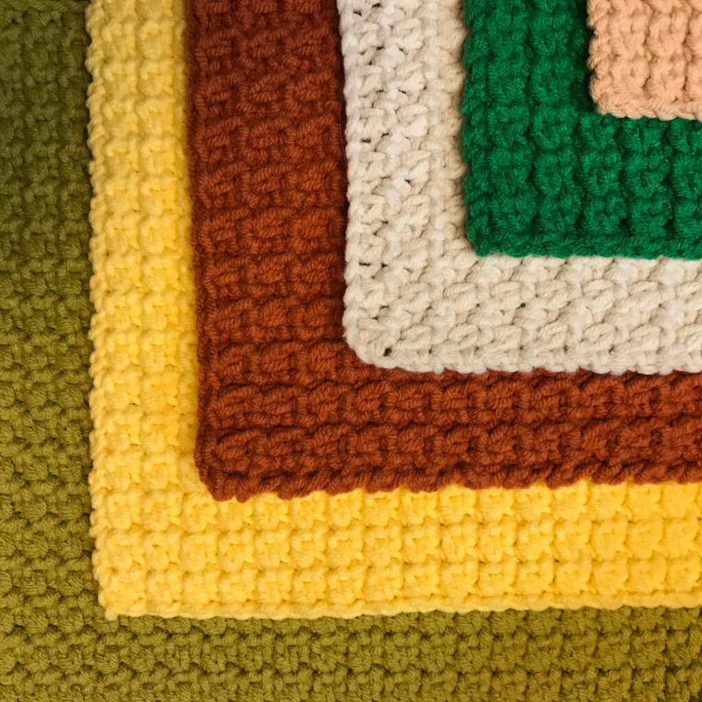 Close-up of colorful crocheted fabric layers showcasing texture and pattern.