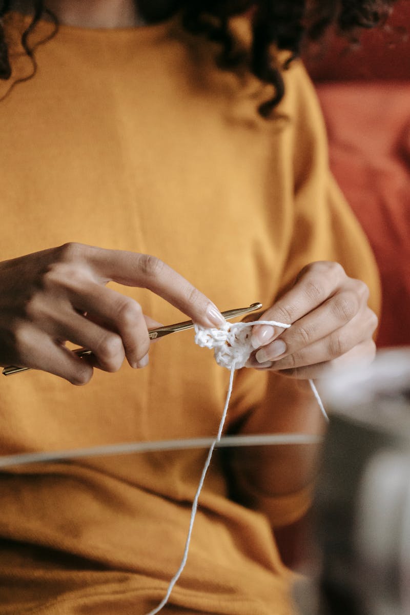 A close-up of a woman crocheting with focus on her hands and yarn, highlighting her hobby and craftsmanship.