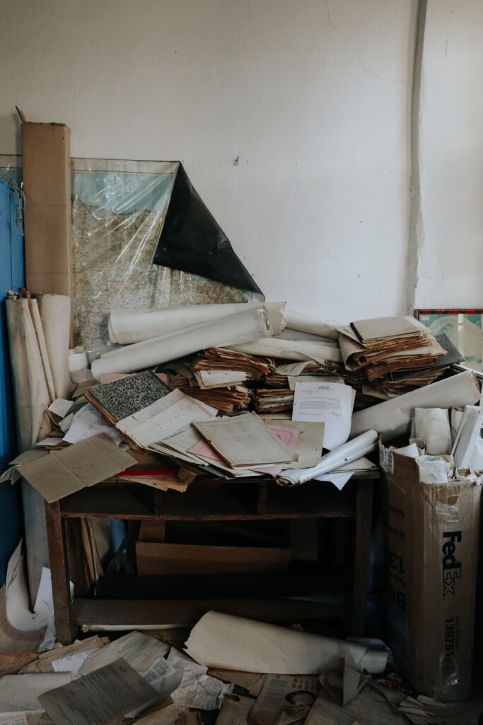 Why Willpower Isn't Your Problem (Your Environment Is) An abandoned desk piled with old papers and documents in a disorganized setting.